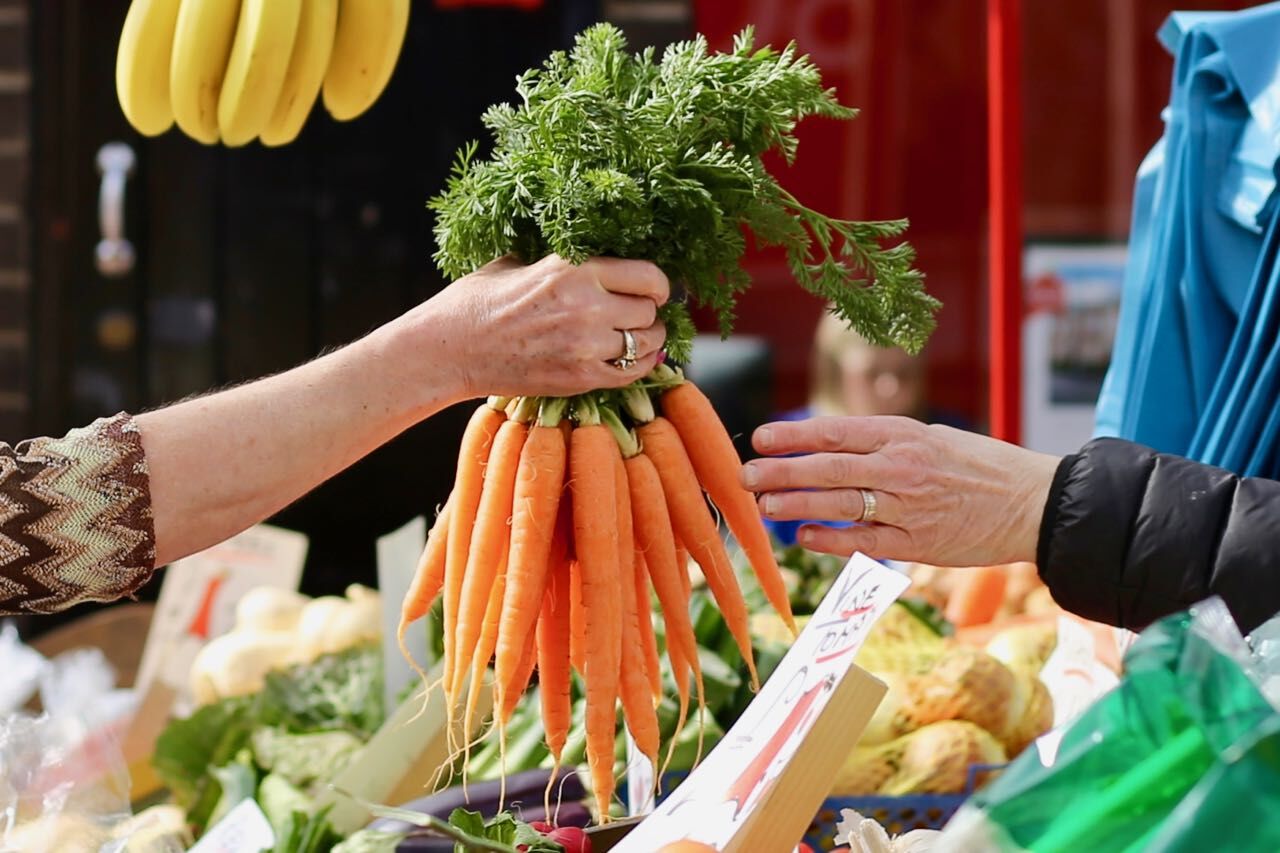 Things to do in East Cambridgeshire - Families. Ely Market. Close up of a bunch of carrots on a green grocers stall
