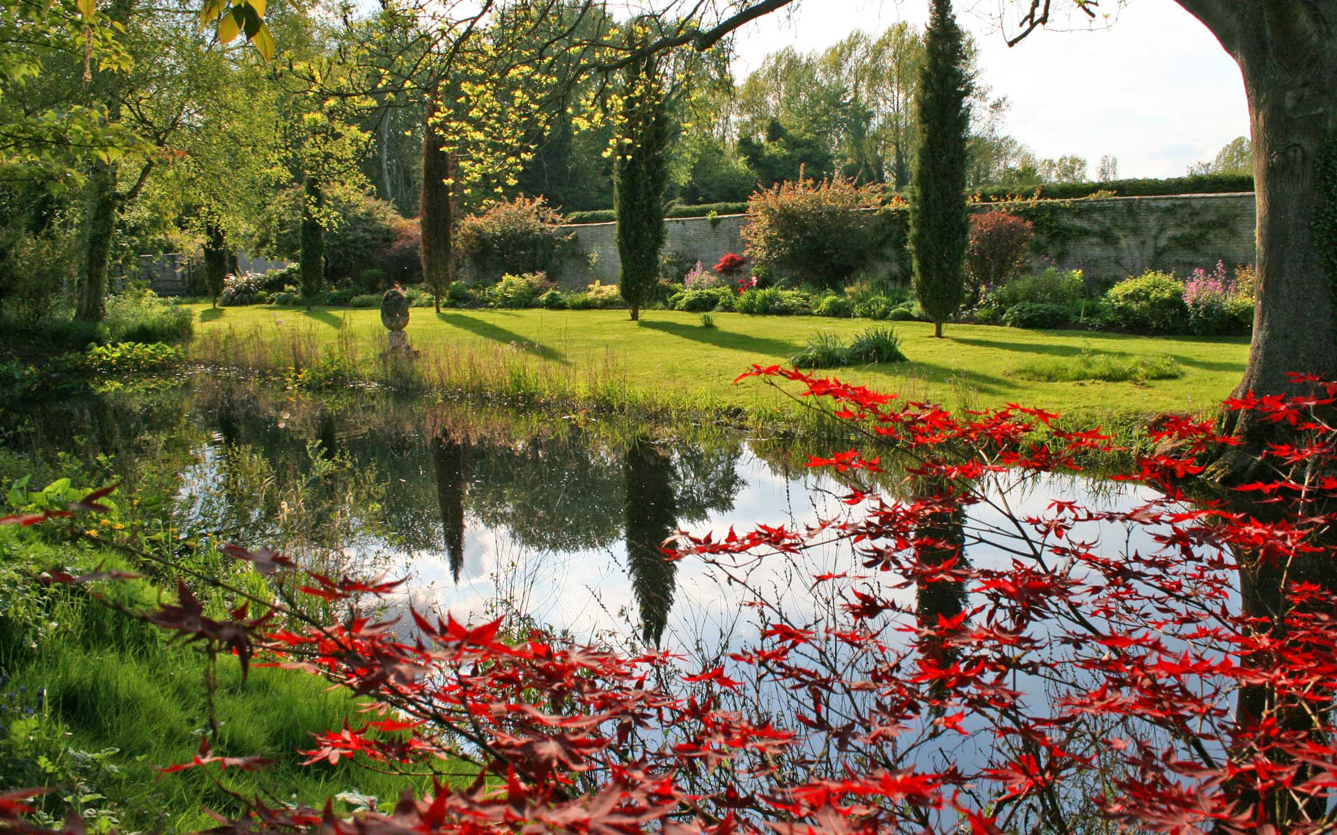 Things to do in East Cambs in Spring - Chippenham Gardens Easter Egg Hunt. Lake in Chippenham Gardens surrounded by bushes and shrubs.