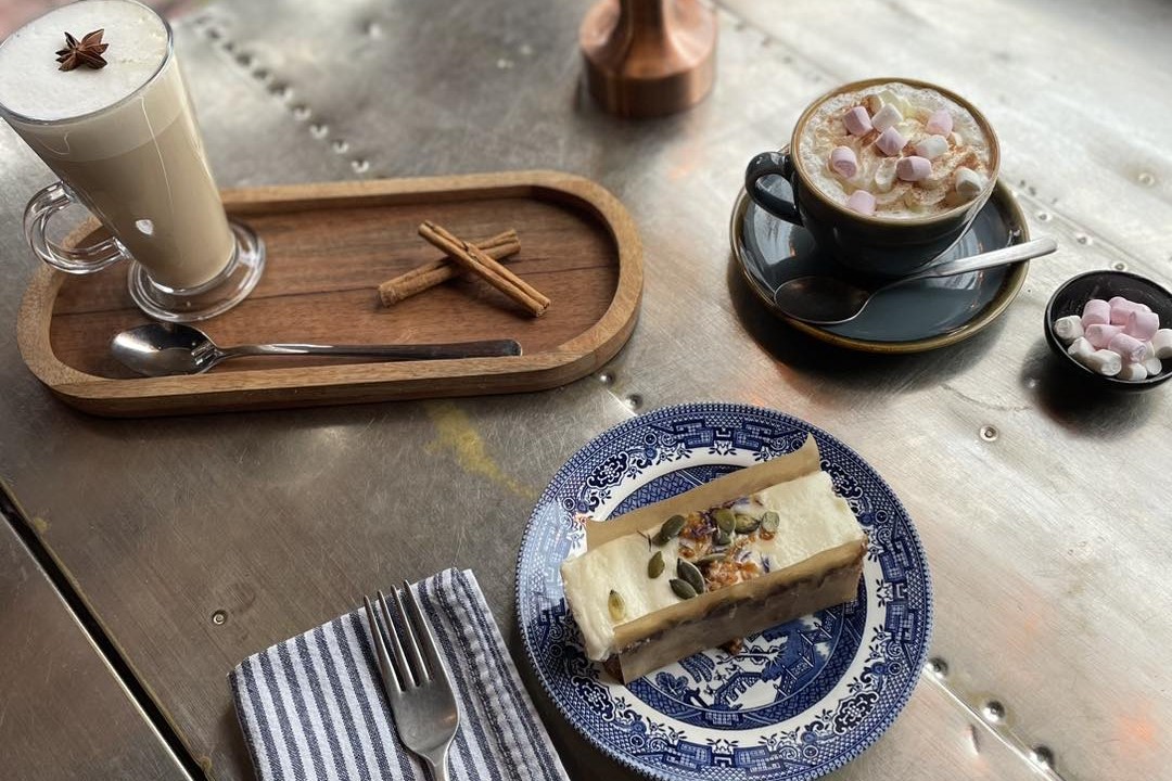 Places to eat in East Cambridgeshire - CornerCopia. Image of coffee, hot chocolate and slice of cake arranged on table